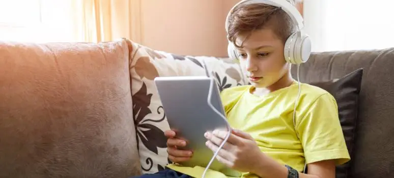 Young boy experiences benefits of audiobooks by listening to audio books on a tablet